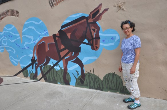 Eurhi Jones with one piece of the mural that represents a time when mules would carry boats along the canal. (Greta Iverson/for NewsWorks)